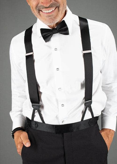 Man wearing a white dress shirt, black bow tie, and suspenders against a gray background