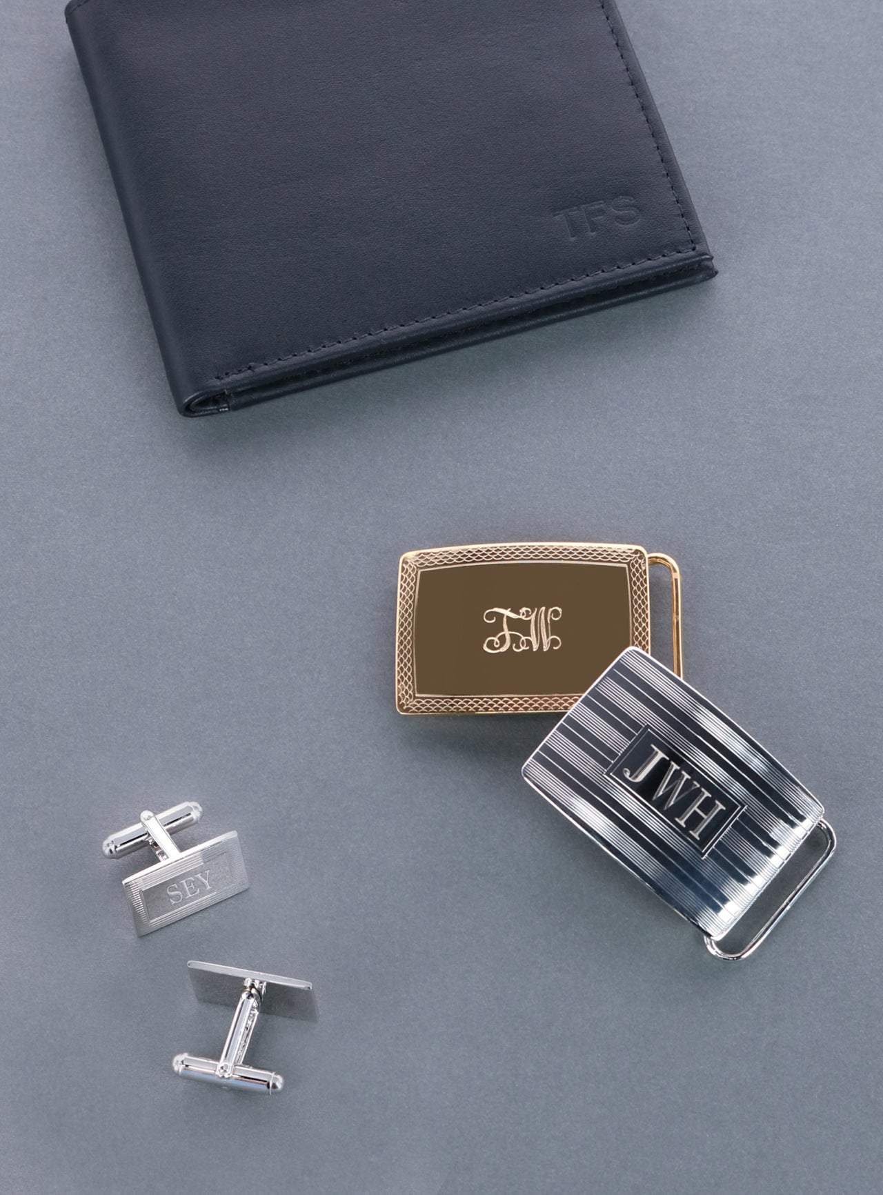 A wallet, cufflinks, and two belt buckles with monograms