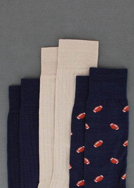 Three pairs of socks in navy, beige, and navy with football pattern on a gray background